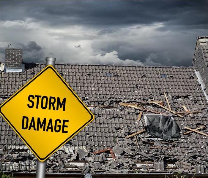 Yellow storm damage sign in front of a damaged roof